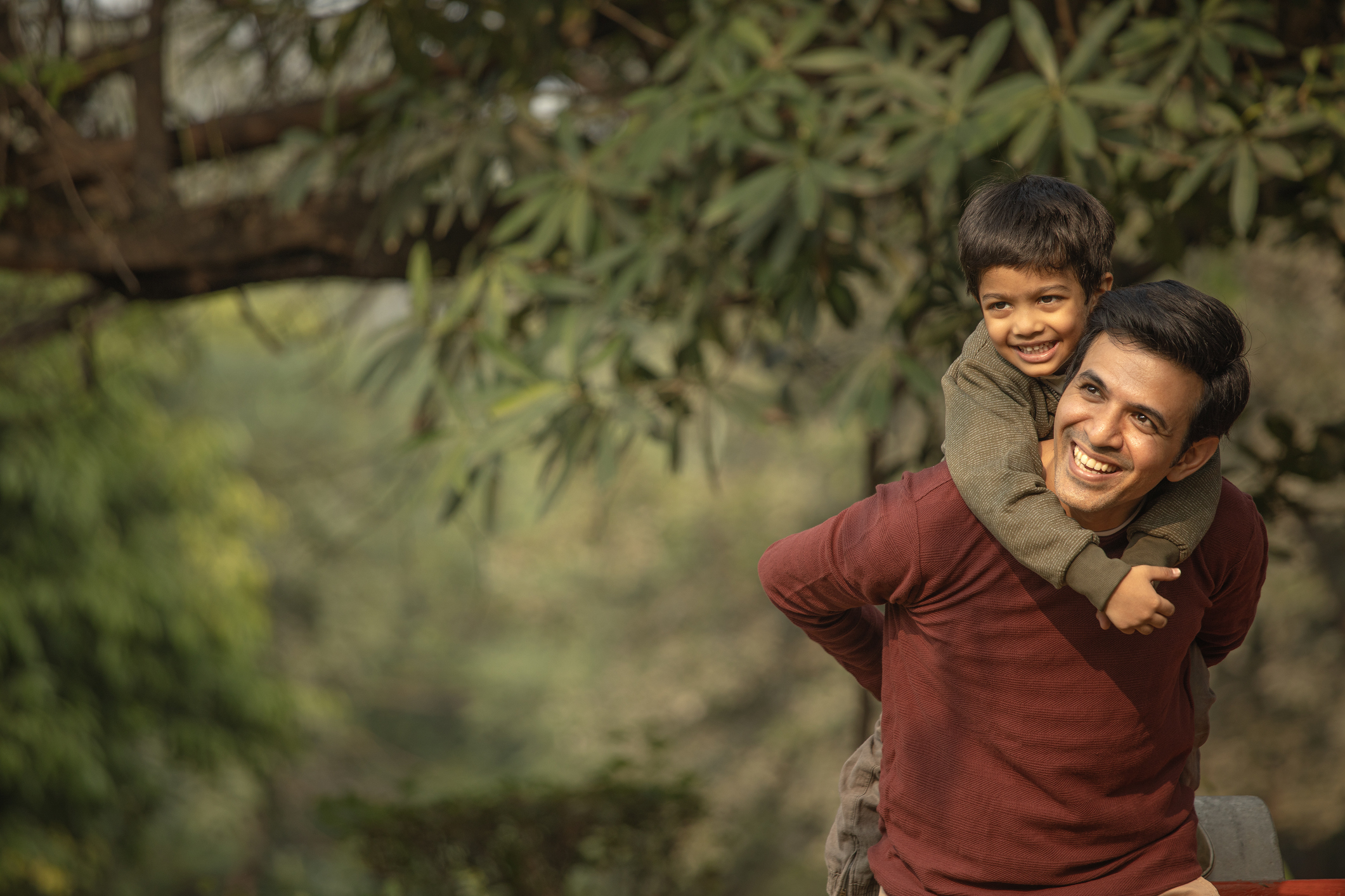 Happy father piggybacking son in garden