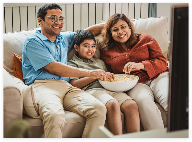Family sitting on couch eating popcorn