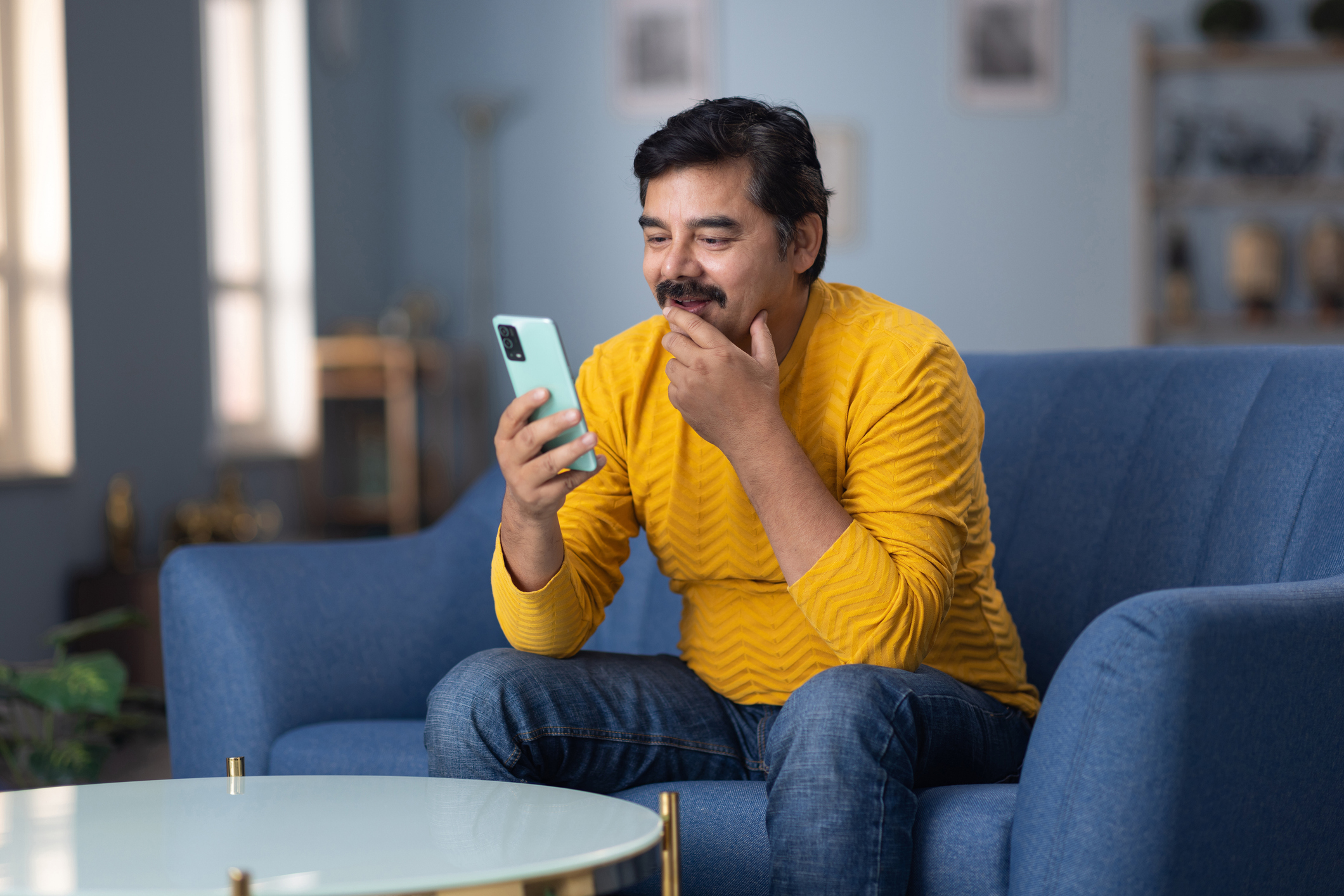 Man using phone sitting on sofa at home stock photo